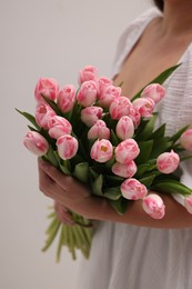 Photo of Woman with bouquet of beautiful fresh tulips on light grey background, closeup