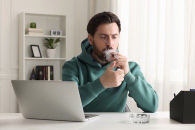 Photo of Man using cigarette holder for smoking at workplace in office