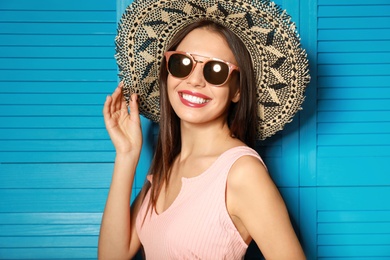 Photo of Beautiful woman wearing sunglasses and hat near blue wooden folding screen