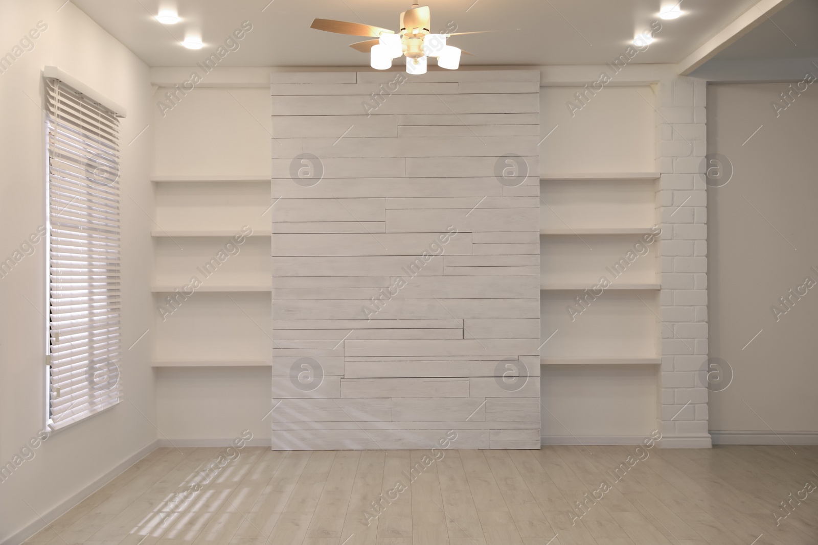 Photo of Empty room with textured wall, stylish wooden shelves and large window