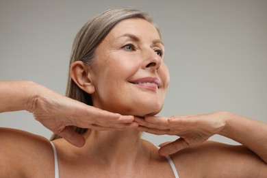 Photo of Beautiful woman touching her neck on grey background, low angle view