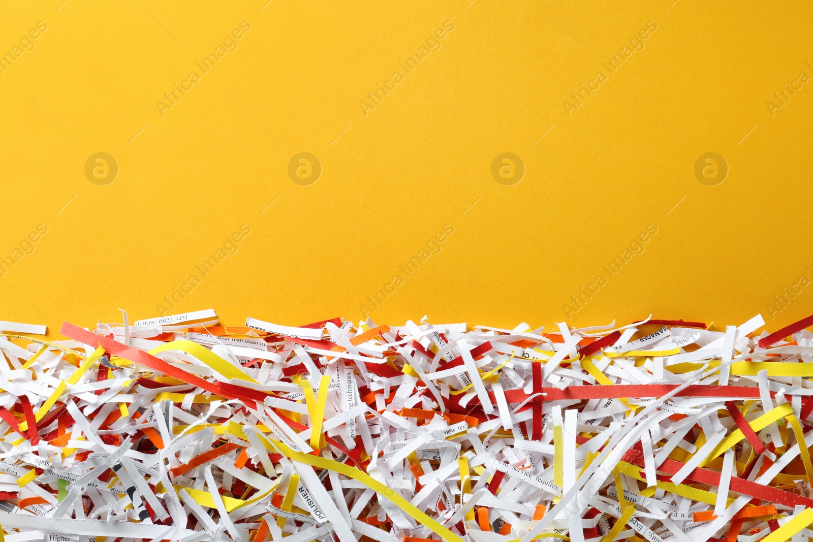 Photo of Shredded colorful paper strips on orange background, flat lay. Space for text