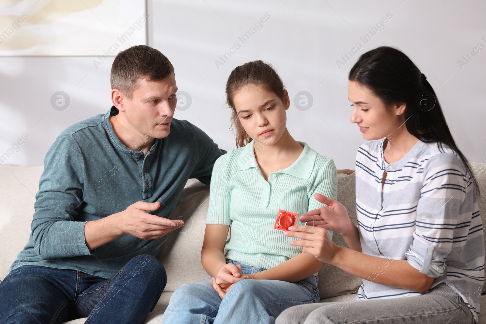 Photo of Parents talking with their teenage daughter about contraception at home. Sex education concept