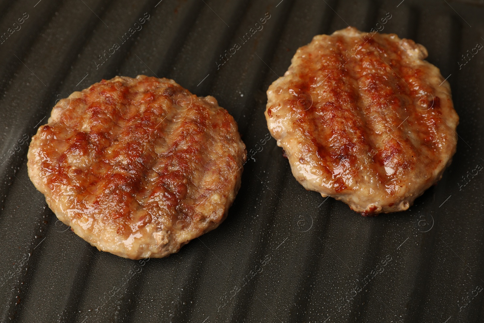 Photo of Tasty hamburger patties on grill pan, closeup