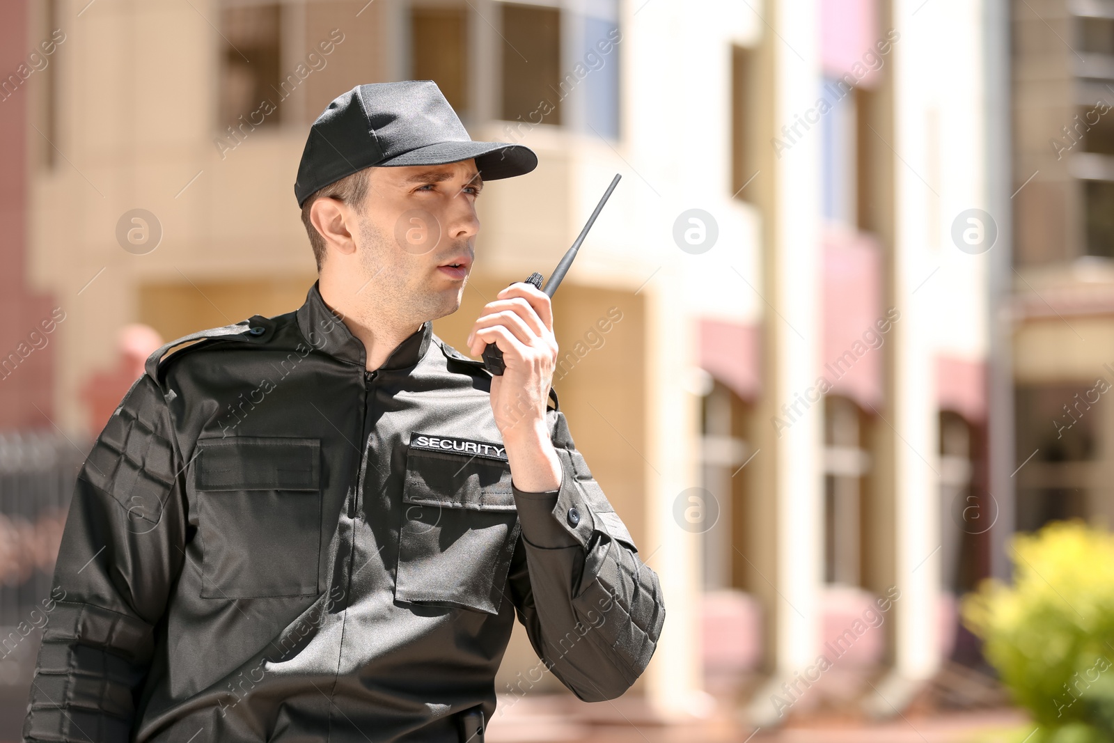 Photo of Male security guard using portable radio transmitter outdoors