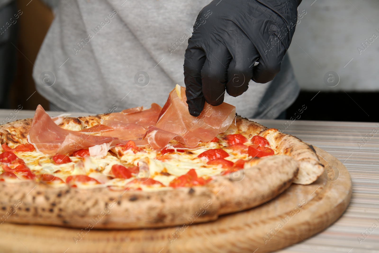 Photo of Professional chef preparing Italian oven baked pizza in restaurant, closeup