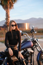 Beautiful young woman sitting on motorcycle outdoors