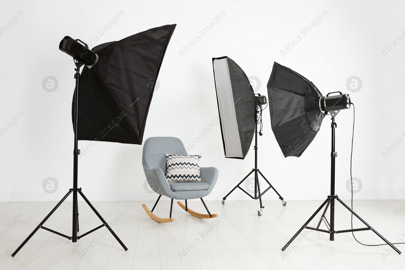 Photo of Comfortable rocking chair and professional lighting equipment in photo studio