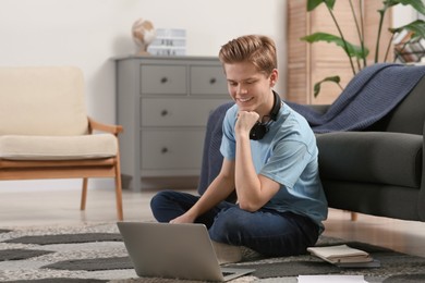 Photo of Online learning. Smiling teenage boy near laptop at home