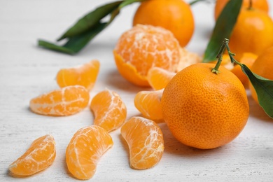 Fresh ripe tangerines with green leaves on table