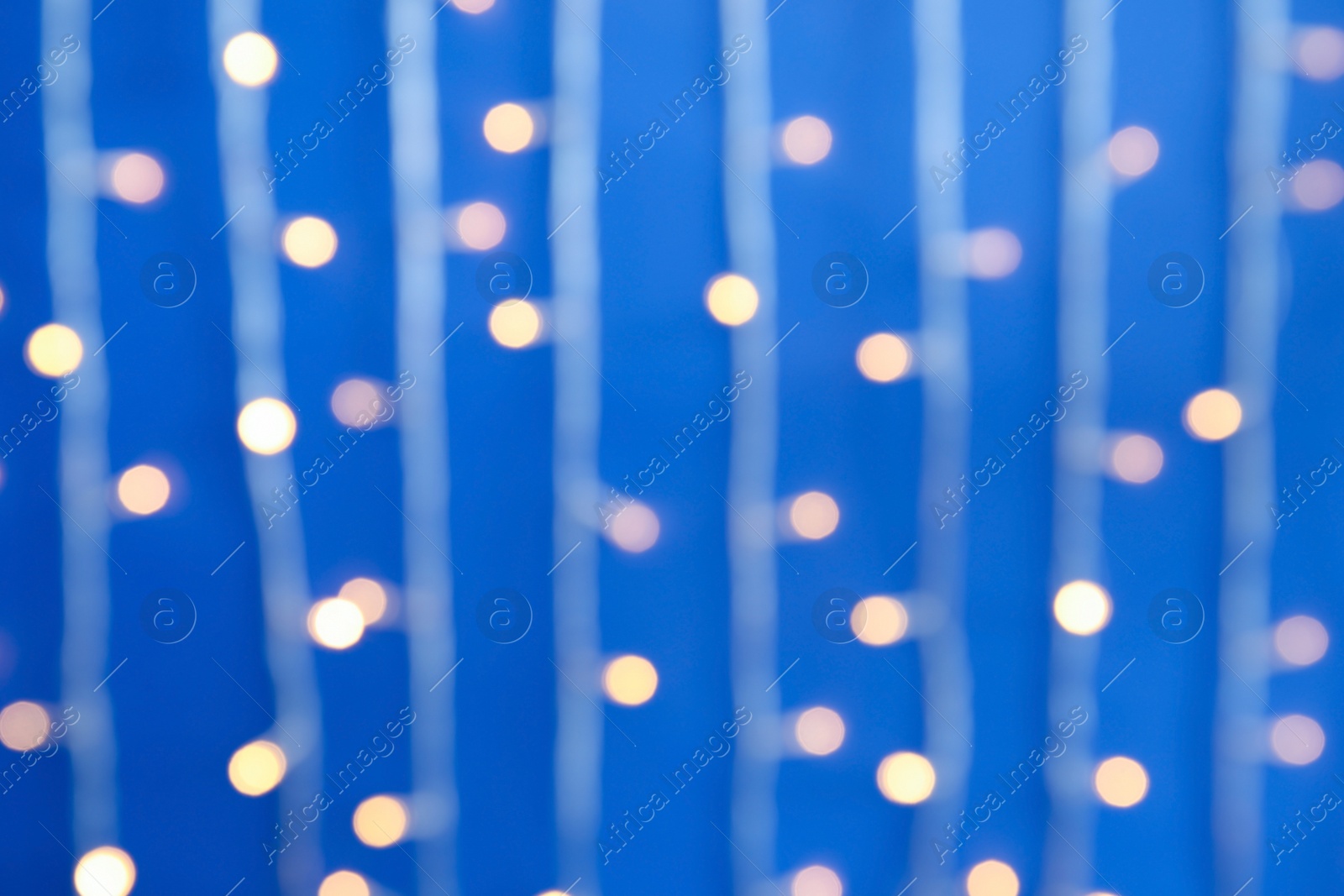 Photo of Blurred view of Christmas lights on color background