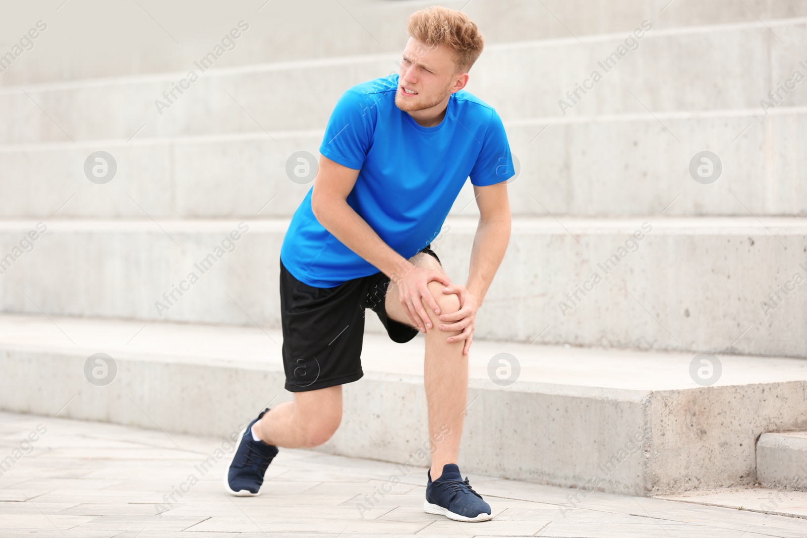 Photo of Man in sportswear suffering from knee pain on stairs