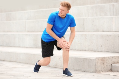 Man in sportswear suffering from knee pain on stairs