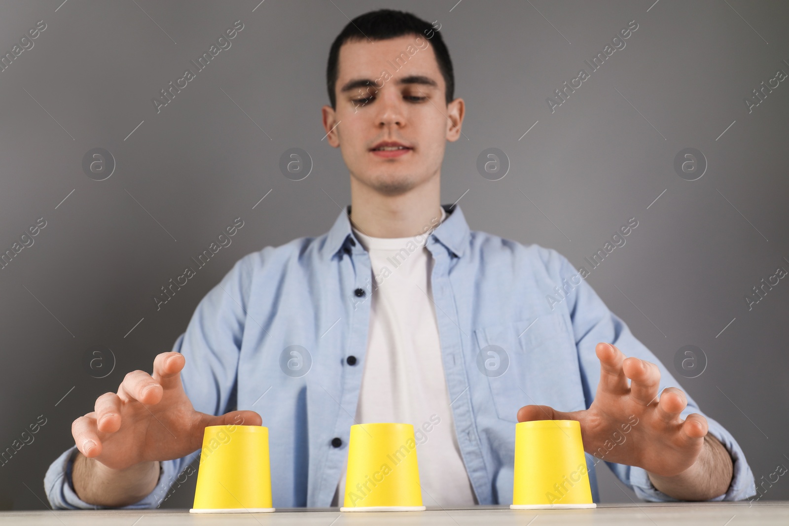 Photo of Man playing shell game at table, low angle view