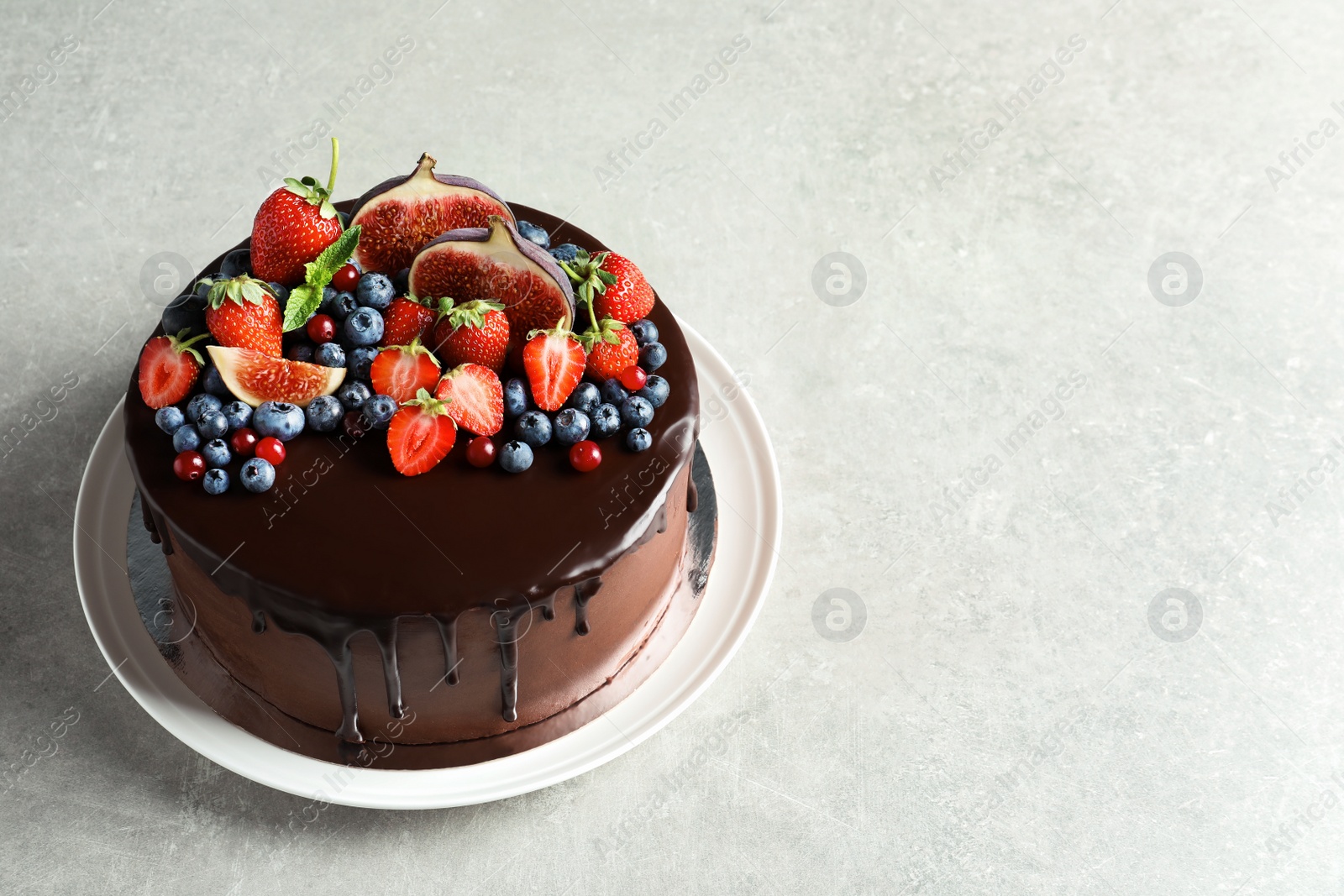 Photo of Fresh delicious homemade chocolate cake with berries on gray table. Space for text