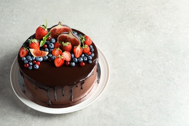 Fresh delicious homemade chocolate cake with berries on gray table. Space for text