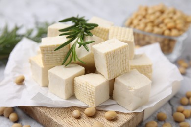 Photo of Delicious tofu cheese, rosemary and soybeans on wooden board, closeup