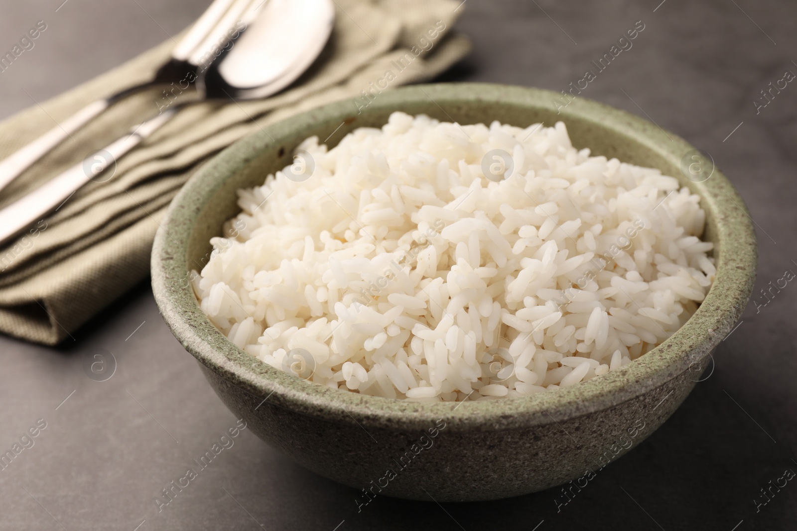 Photo of Delicious rice in bowl on grey table, closeup