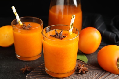 Tasty persimmon smoothie with anise and fresh fruits on black table