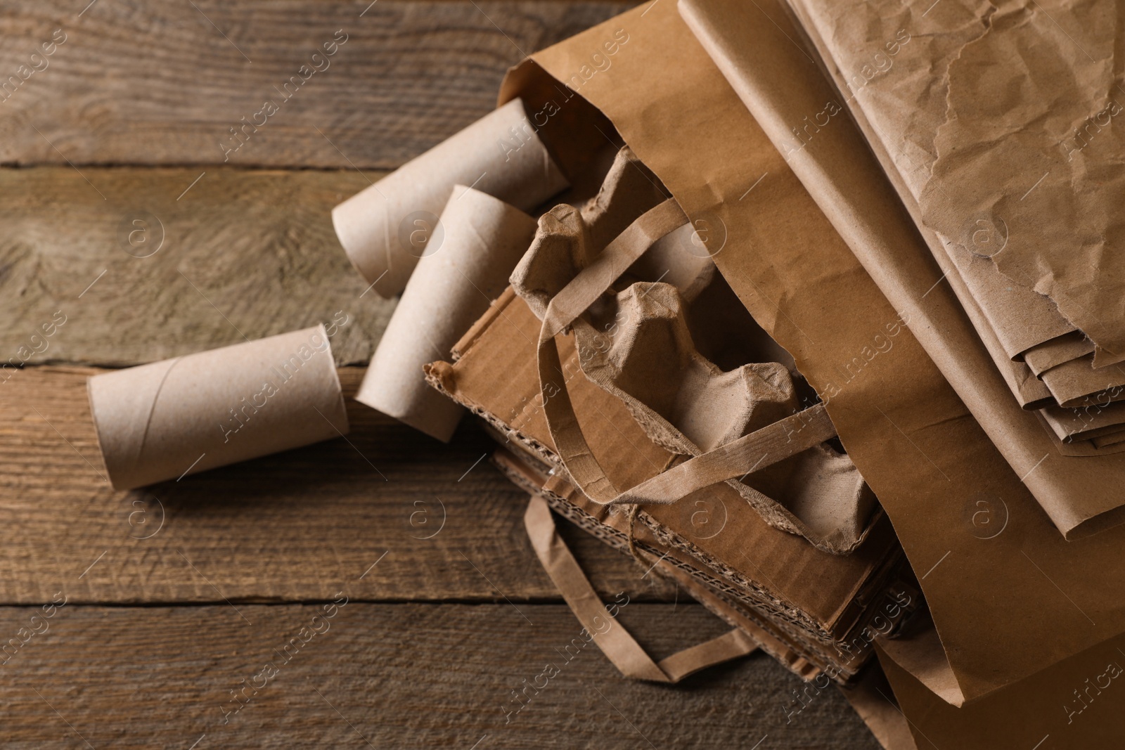 Photo of Different waste paper on wooden table, closeup. Space for text