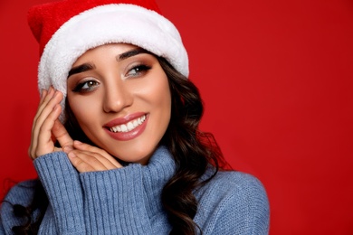 Photo of Beautiful woman in Santa hat on red background. Christmas party