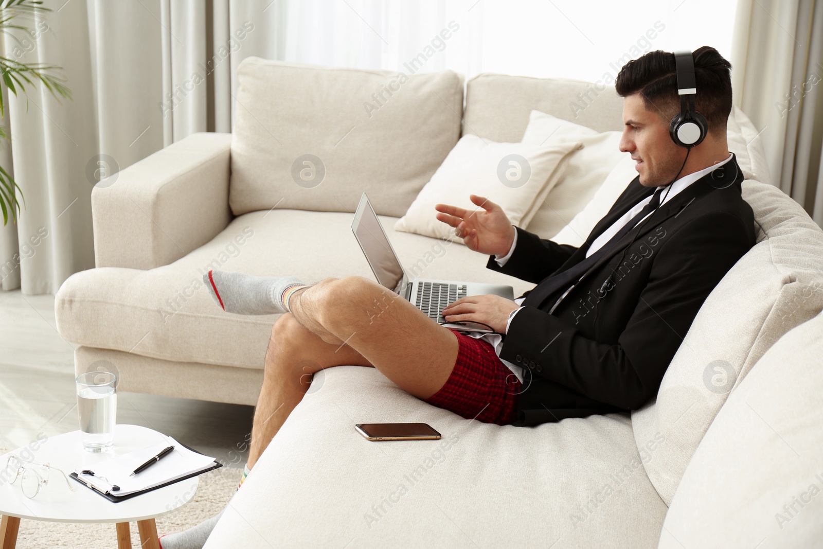 Photo of Businessman in jacket and underwear having videocall on laptop at home