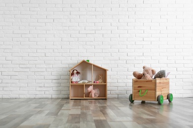Wooden storage with toys near white brick wall in baby room interior