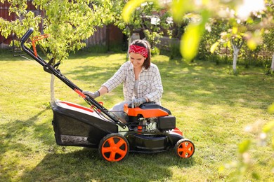 Photo of Smiling woman with lawn mower in garden on sunny day