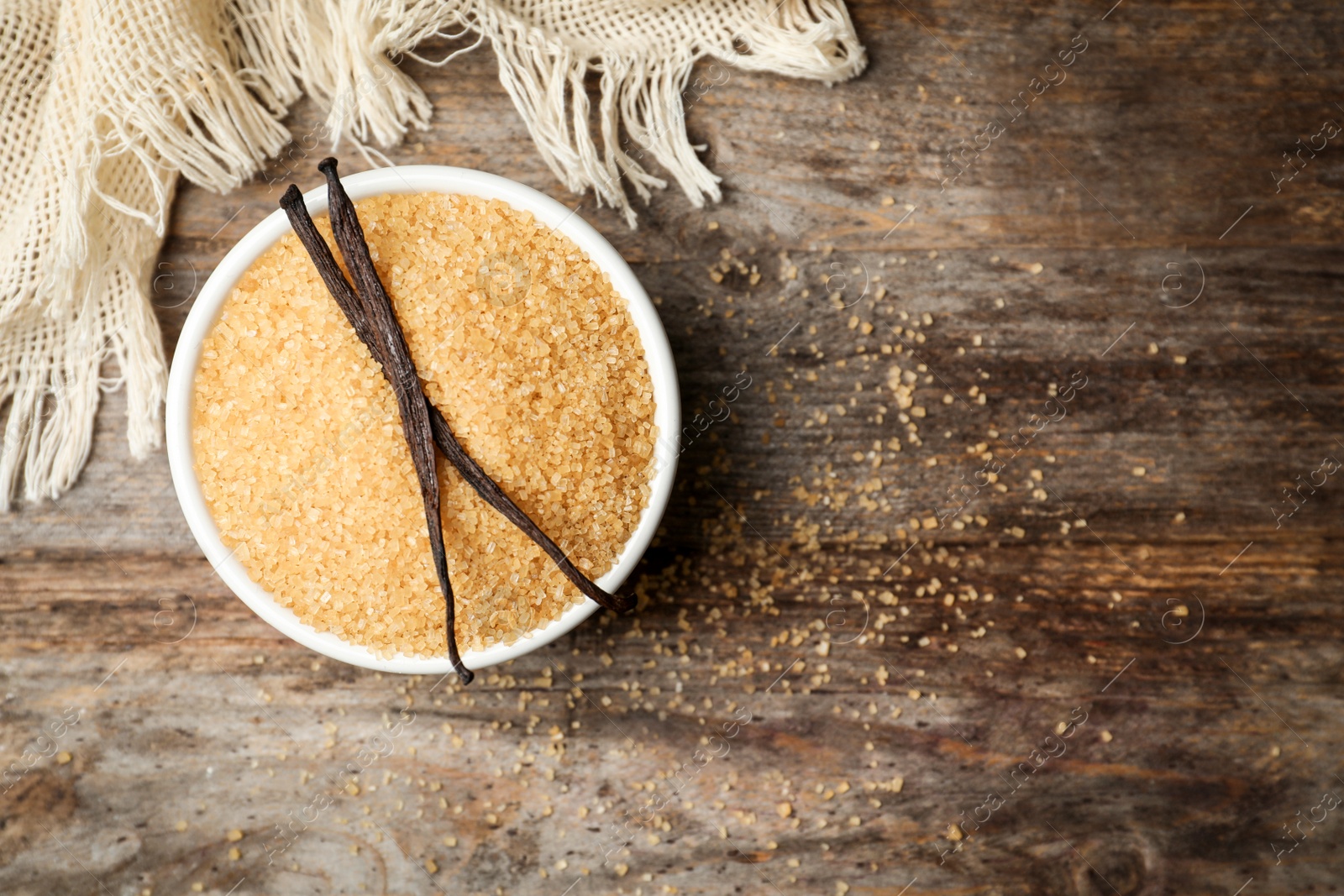 Photo of Bowl of aromatic vanilla sugar and sticks on wooden background