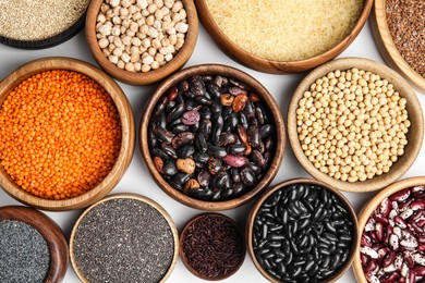 Photo of Various raw veggie seeds in bowls on white background, top view