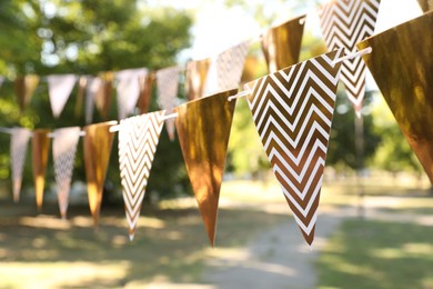 Golden bunting flags in park. Party decor