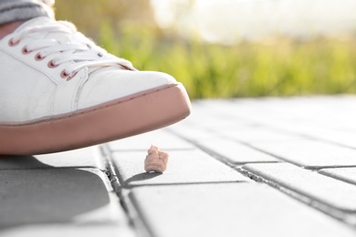 Woman stepping in chewing gum on sidewalk. Concept of stickiness