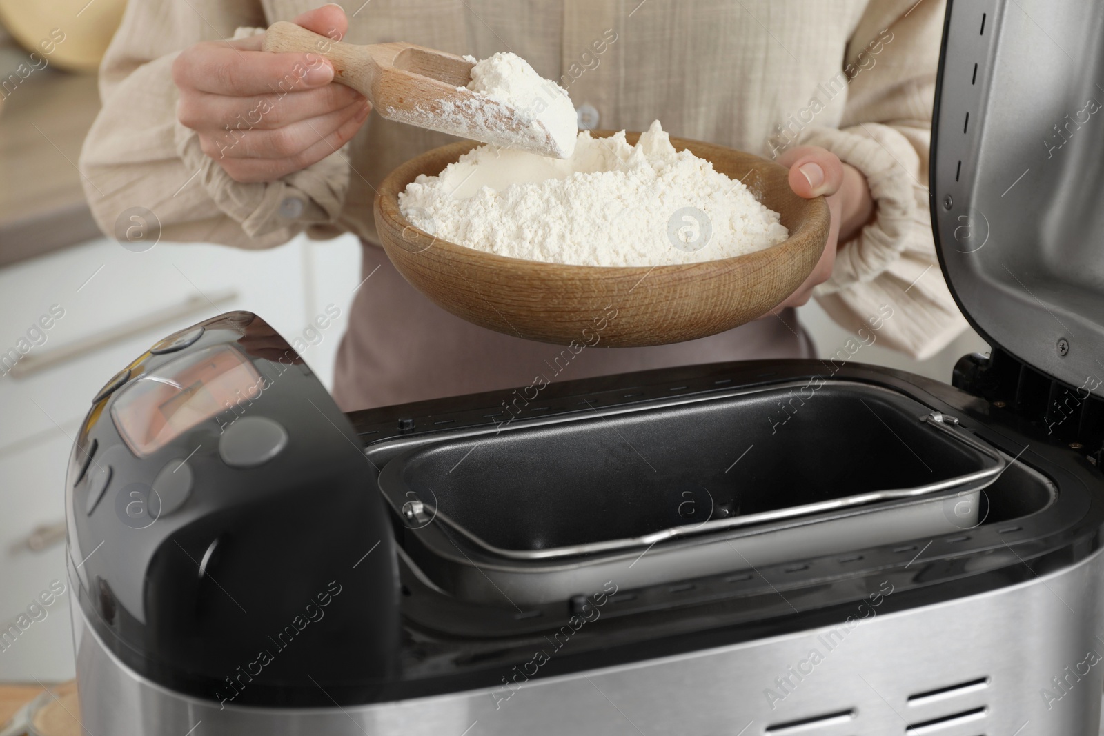 Photo of Making dough. Woman adding flour into breadmaker machine, closeup