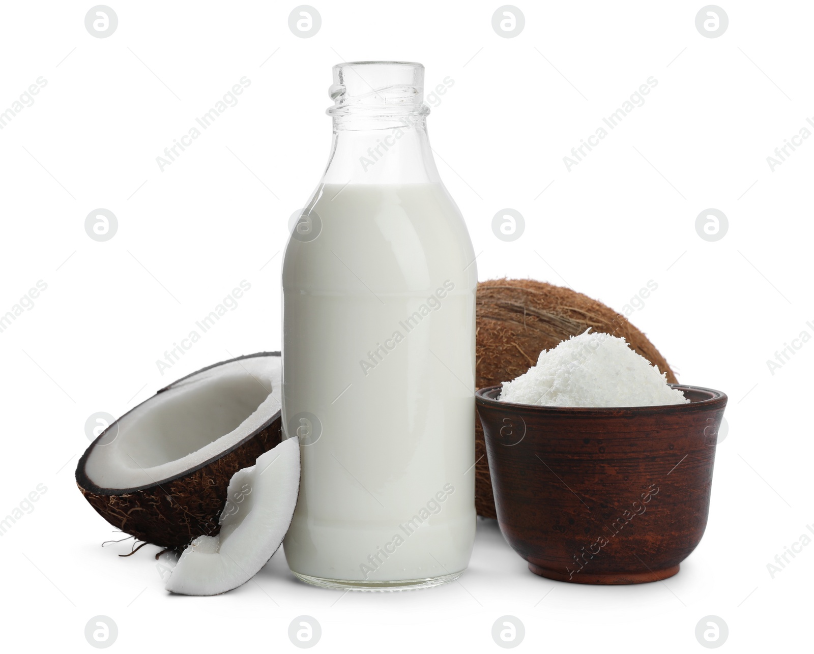 Photo of Bottle of delicious coconut milk, bowl with flakes and nuts on white background