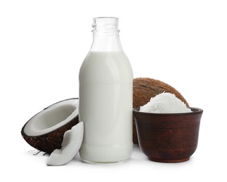 Photo of Bottle of delicious coconut milk, bowl with flakes and nuts on white background