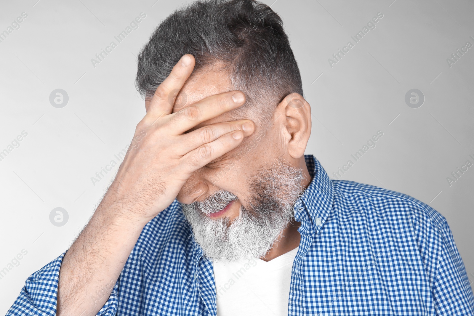 Photo of Man suffering from headache on light background