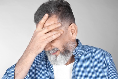 Man suffering from headache on light background