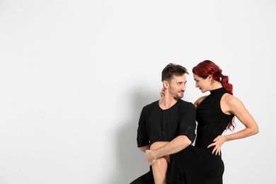 Beautiful young couple dancing in studio, space for text