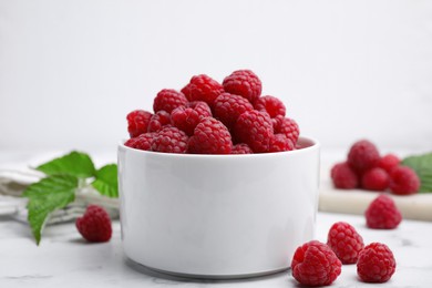 Photo of Bowl with fresh ripe raspberries on white marble table