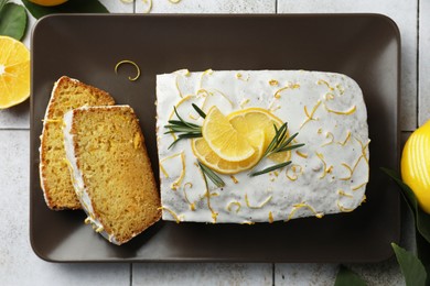Photo of Tasty lemon cake with glaze and citrus fruits on table, top view