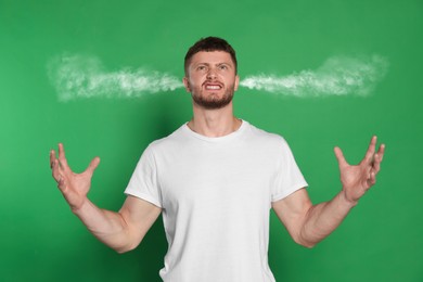 Aggressive man with steam coming out of his ears on green background