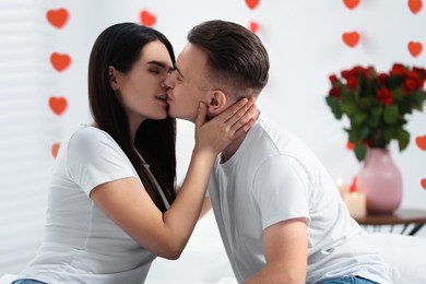 Photo of Lovely couple kissing on bed indoors. Valentine's day celebration