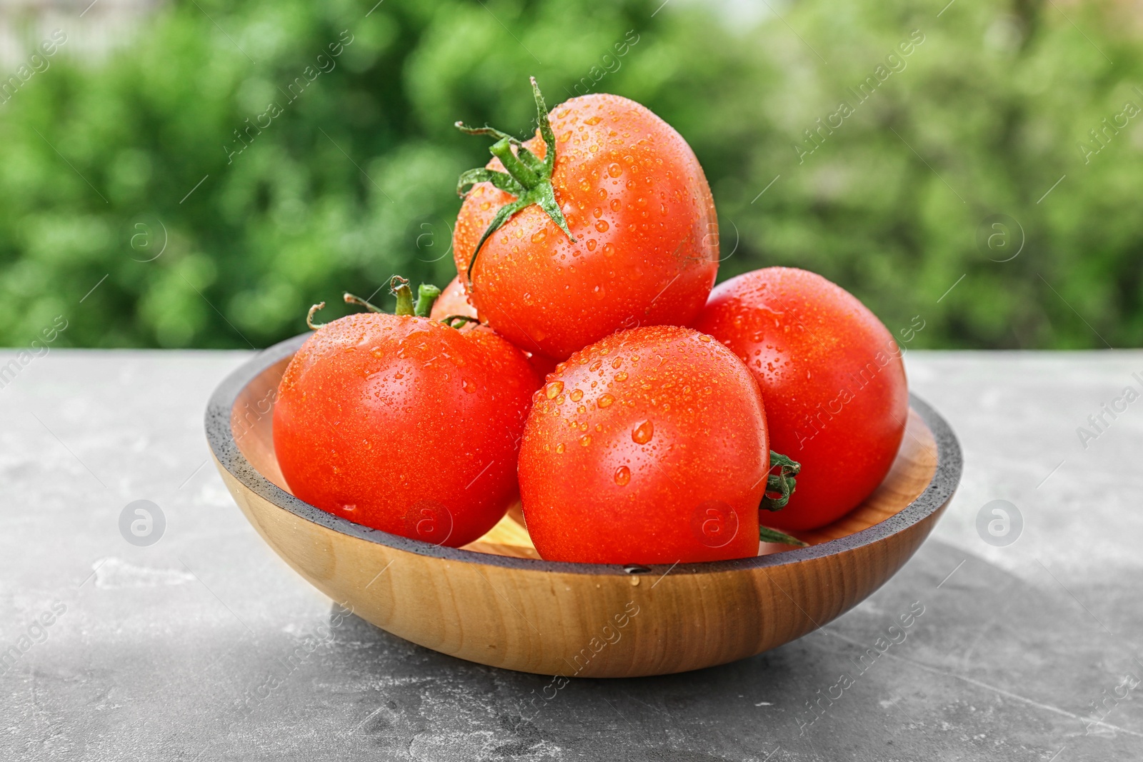 Photo of Plate with fresh ripe tomatoes on table outdoors