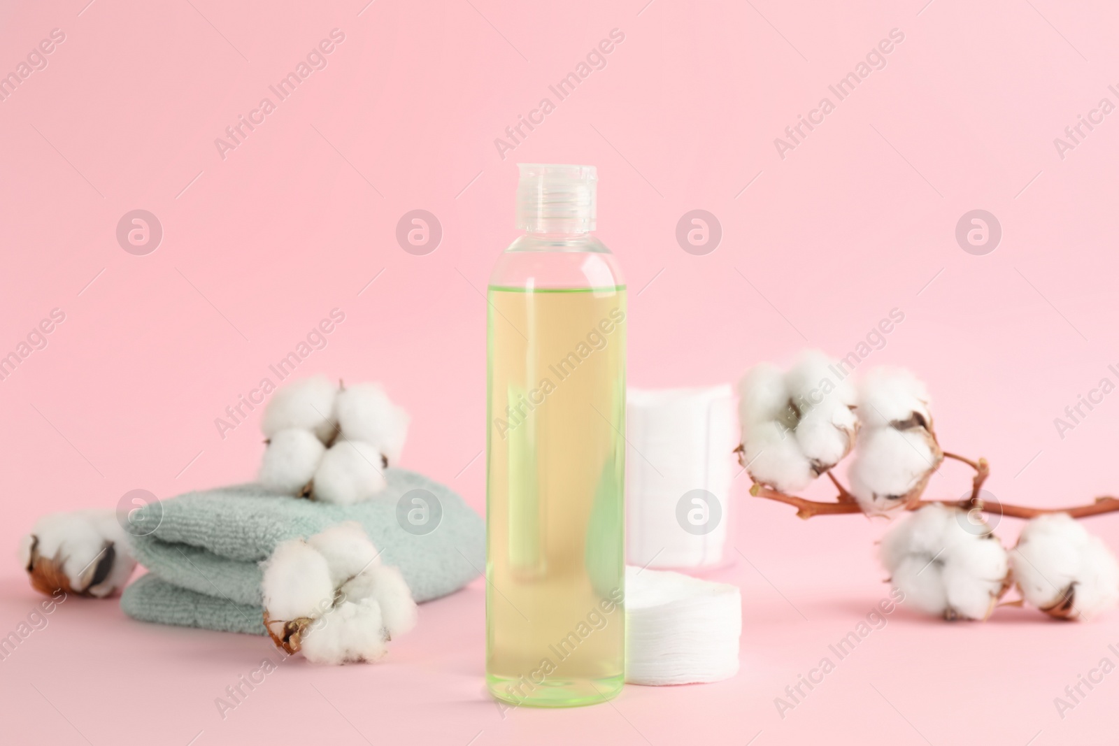 Photo of Cotton pads, towel, dry flowers and makeup removal product on pink background