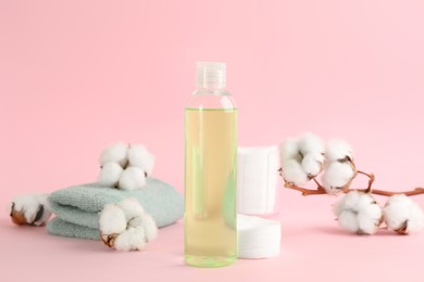 Cotton pads, towel, dry flowers and makeup removal product on pink background