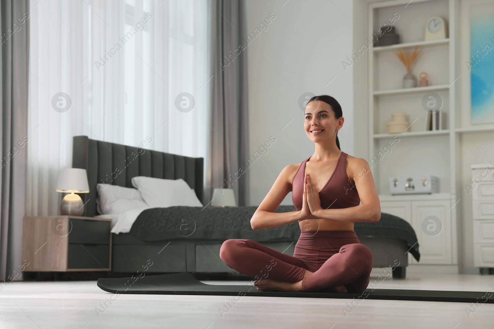 Photo of Beautiful young woman Padmasana on yoga mat at home, low angle view. Lotus pose