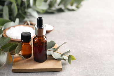 Photo of Aromatherapy. Bottles of essential oil and eucalyptus leaves on grey table, space for text