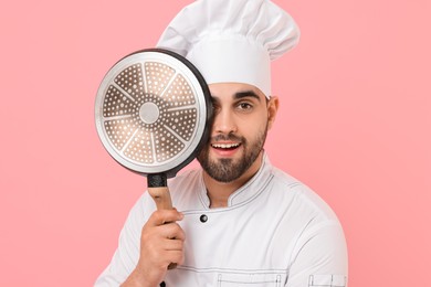 Photo of Professional chef with frying pan on pink background