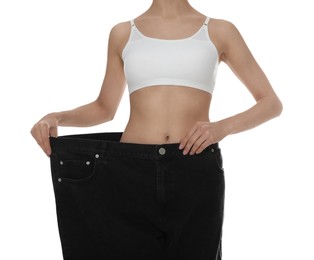 Photo of Young woman wearing big jeans after weight loss on white background, closeup