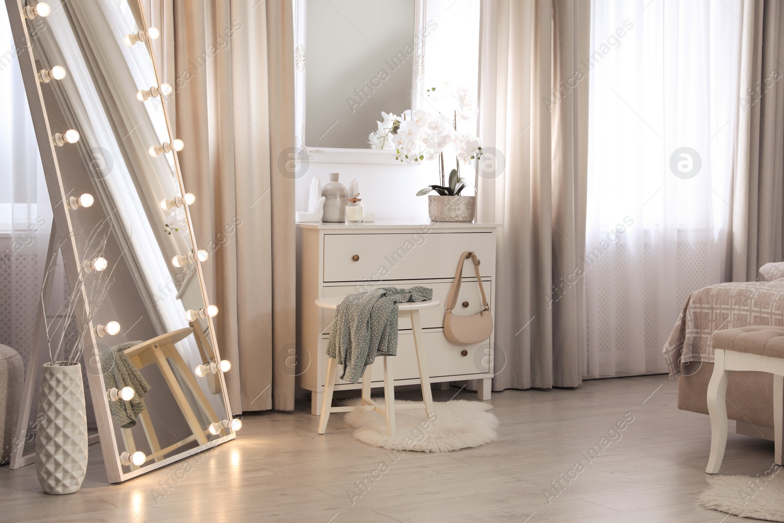 Photo of Large mirror with light bulbs and chest of drawers in bedroom. Interior design